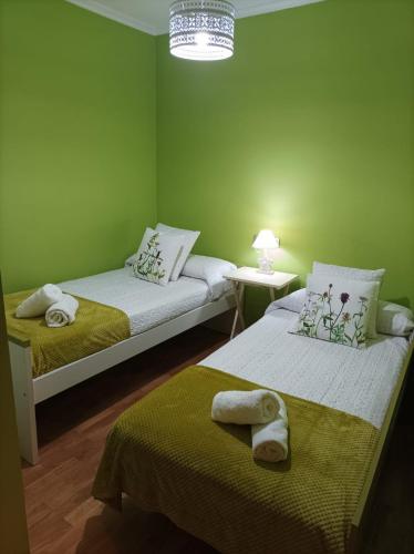 two beds in a green room with towels on them at Apartamento A Rapadoira Foz in Foz