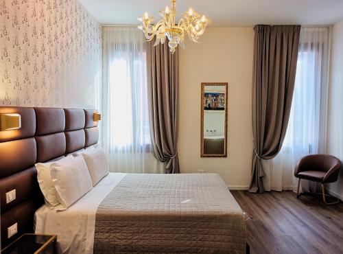 1 dormitorio con cama, espejo y lámpara de araña en Palazzo Orseolo- Gondola View, en Venecia