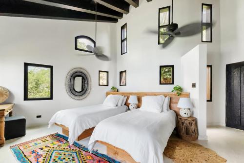 two beds in a bedroom with white walls and a rug at The Aerial, BVI in Tortola Island