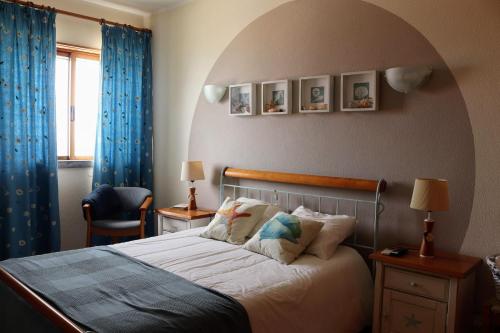 Schlafzimmer mit einem großen Bett und blauen Vorhängen in der Unterkunft Starfish Beach House in São Pedro de Muel