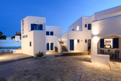 a large white building with a patio in front of the water at Hotel Bilia in Naousa
