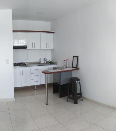 a kitchen with white cabinets and a wooden table at APARTAESTUDIO SENDERO PRIMAVERA 2 in Neiva
