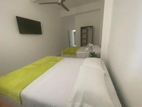 a bedroom with a large white bed and a tv at Hotel Sabana Inn in San José