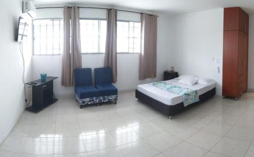a bedroom with a bed and a chair and windows at APARTAESTUDIO SENDERO PRIMAVERA 2 in Neiva