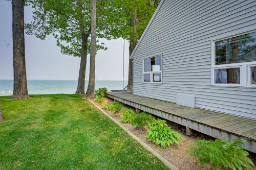 a house with a porch next to the ocean at Vibrant Waterfront Vacation Rental on Lake Huron! in Tawas City