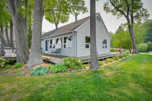 a white house with a porch and trees at Vibrant Waterfront Vacation Rental on Lake Huron! in Tawas City