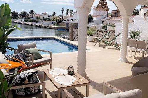 um pátio com uma piscina, cadeiras e uma mesa em Casa Serenity au canal avec piscine et amarre em Empuriabrava