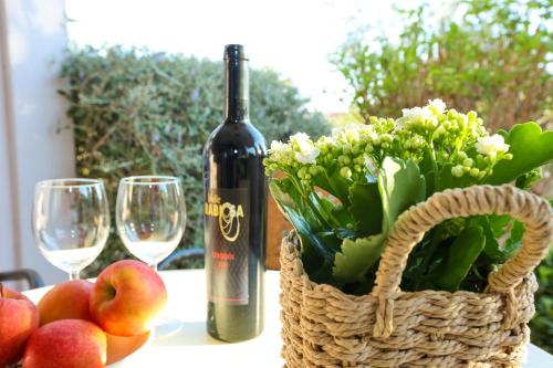 eine Flasche Wein und ein Korb mit Blumen und Äpfeln in der Unterkunft Apartments Vallis Rabiosa in Zadar