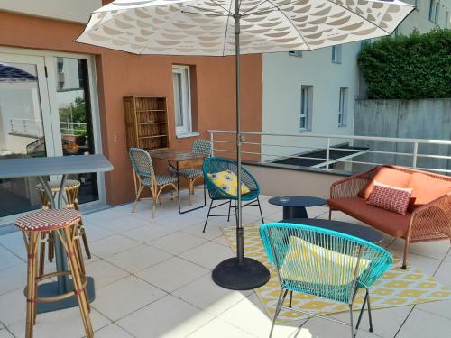 une terrasse avec des chaises, des tables et un parasol dans l'établissement Aparthotel Adagio Access Dijon République, à Dijon