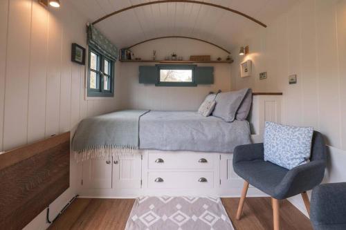 a bed and a chair in a small room at Dipper's Hut - Luxury Shepherds Hut with Hot Tub in Blakeney