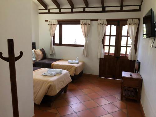 Cette chambre comprend deux lits, un canapé et une fenêtre. dans l'établissement Hotel Calle Principal, à Sáchica
