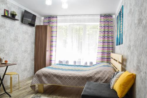 niewielka sypialnia z łóżkiem i oknem w obiekcie YourHouse на Си Синхая недалеко от Меги w mieście Ałma-Ata