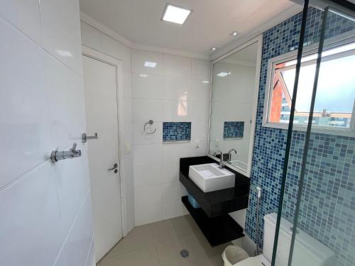 La salle de bains blanche est pourvue d'un lavabo et d'une douche. dans l'établissement FLAT RIVIERA COM AR A 150 m DA PRAIA !, à Riviera de São Lourenço