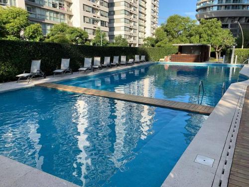 una grande piscina blu con sedie e edifici di Luxury Apartment V. López a Vicente López