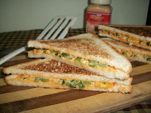 three sandwiches on a wooden cutting board with a fork at Hermitage Riviera in Arpora