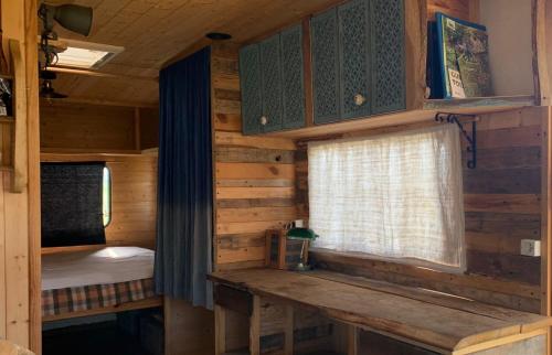 Cabaña de madera con cama y ventana en la cabane mobile en Beyssenac