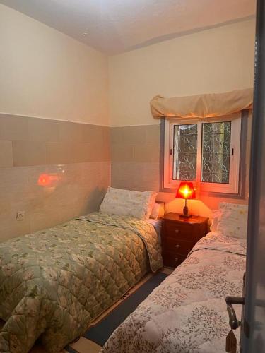 a bedroom with two beds and a window at Hôtel Restaurant ASGAOUR in Amlouggui