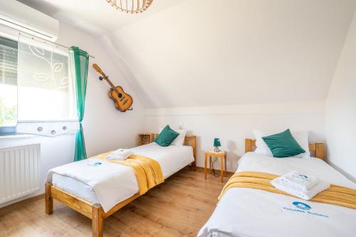 2 Betten in einem Zimmer mit einer Gitarre an der Wand in der Unterkunft KAWAŁEK ŚWIATA in Darłowo