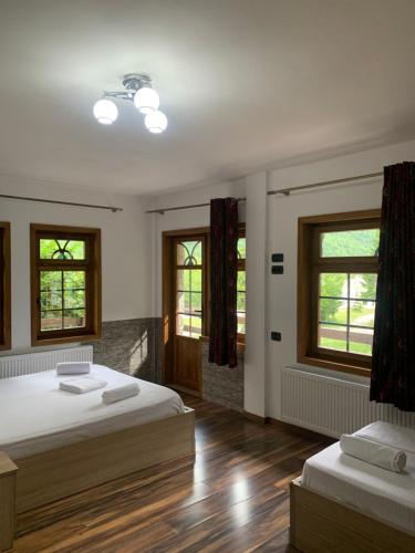 a bedroom with two beds and two windows at Fusha e Gjes Hotel in Valbonë