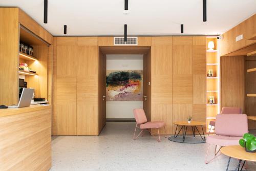a room with wooden cabinets and pink chairs and a table at Lisetta Gardens Boutique & Suites in Cisternino