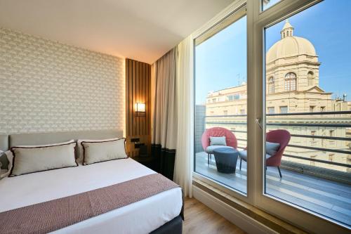 um quarto de hotel com uma cama e uma grande janela em Catalonia Ramblas 4* Sup em Barcelona