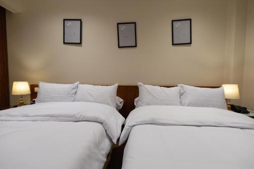 2 camas con sábanas blancas y cuadros en la pared en Marron studios 5 new, en El Cairo