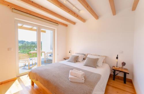 a white bedroom with a large bed and a large window at Monte da Várzea da Rainha in Óbidos