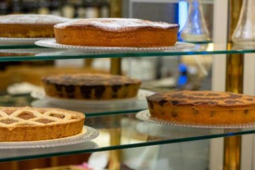 a bunch of cakes on display in a glass case at Hotel Il Chiostro by LVG Hotel Collection in Verbania