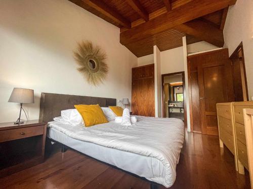 a bedroom with a bed with white sheets and yellow pillows at Cal Peró Casa de montaña in Caixáns