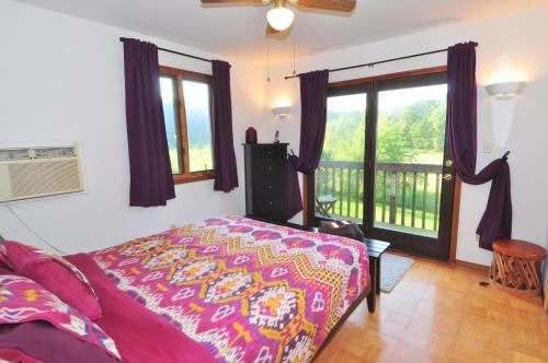 1 dormitorio con 1 cama y balcón en River Valley Cabin - Riverfront Cabin, en Morton Grove
