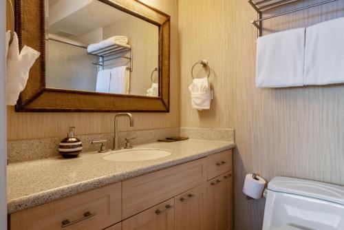 a bathroom with a sink and a mirror and a toilet at Oceanfront Mana Kai 2 bedroom condo in Wailea