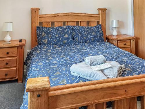 um quarto com uma cama de madeira com lençóis e almofadas azuis em Cairn View em Strachan