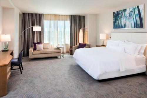 a hotel room with a large white bed and a desk at The Westin Jackson in Jackson