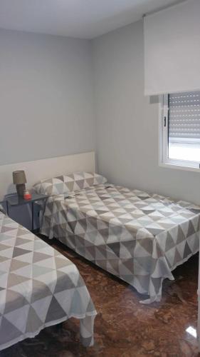 a bedroom with two beds in a room with a window at SAUCES - PARKING GRATIS - CLIMATIZADO in Jaén