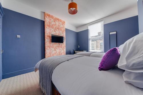 Air Host and Stay - Rockfield Lodge, sleep 12 free parking next to LFC في ليفربول: غرفة نوم بجدران زرقاء وسرير مع وسادة أرجوانية