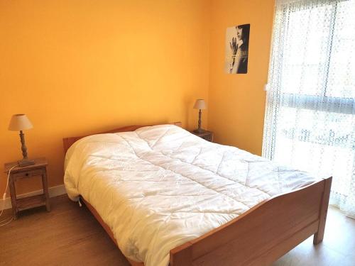 - une chambre dotée d'un grand lit avec des draps blancs et une fenêtre dans l'établissement Appartement avec 2 chambres, balcon et superbe vue mer à quelques pas de la plage de Tresmeur - FR-1-368-148, à Trébeurden