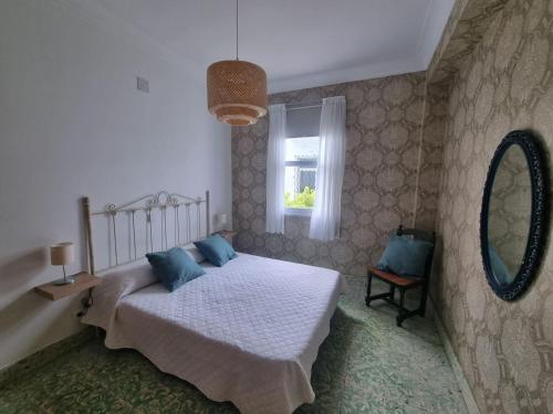 a bedroom with a bed with blue pillows and a mirror at El Chalet Amarillo in Cabañas