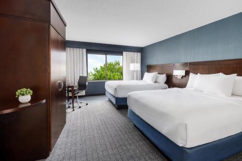 a hotel room with two beds and a desk at Courtyard Manchester-Boston Regional Airport in Manchester