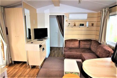 - un petit salon avec un canapé et une télévision dans l'établissement Mobile home 613 6 à 8 pers 44m2 tout équipé, aux Mathes