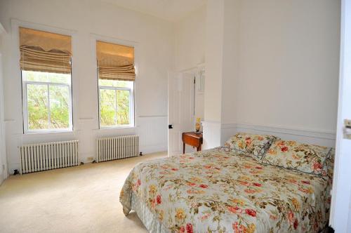 a white bedroom with a bed and two windows at Manor at Berkeley Springs in Berkeley Springs