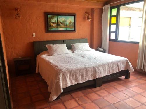 1 dormitorio con 1 cama con sábanas blancas y ventana en HOTEL COMPOSTELLA en Paipa