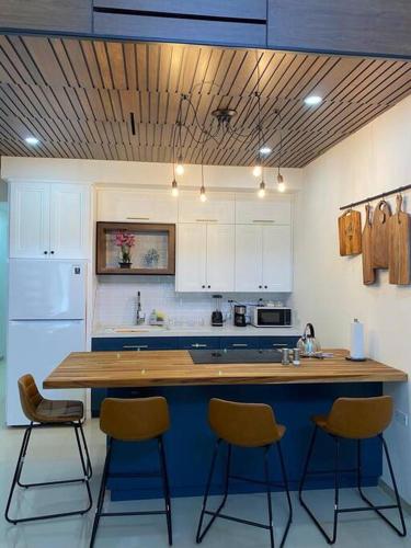 a kitchen with a wooden counter and three bar stools at LOFT 6 UN LUGAR UNICO in Mexicali