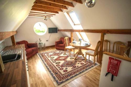 a living room with a red couch and a rug at Topsy-Turvy, Gardeners Cottage, Clungunford, Ludlow, Shropshire SY70PN in Broome