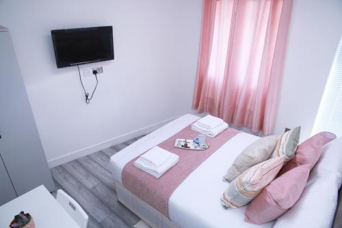 mały pokój z łóżkiem i telewizorem z płaskim ekranem w obiekcie Harrow Luxury flat With free parking. w Londynie