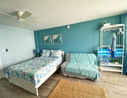 a bedroom with blue walls and a bed and a chair at Sea Dip Resort Studios! in Daytona Beach