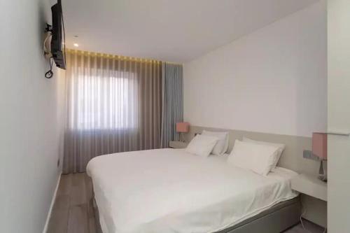 um quarto com uma grande cama branca e uma janela em Bright Lisbon T2 with 35 m2 Terrace, 2bed and 2bath and fast internet! em Lisboa