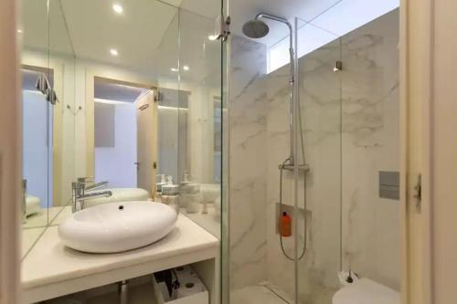 uma casa de banho com um lavatório e uma cabina de duche em vidro. em Bright Lisbon T2 with 35 m2 Terrace, 2bed and 2bath and fast internet! em Lisboa