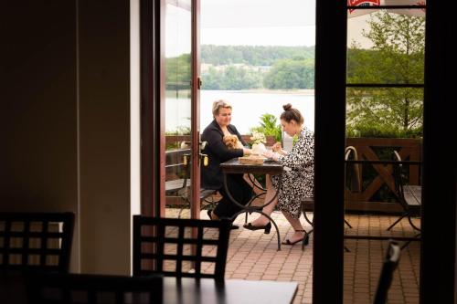 a man and woman sitting at a table on a patio at Hotel Anek in Mrągowo