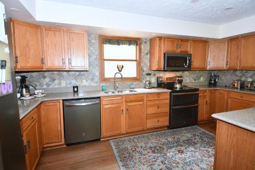 a kitchen with wooden cabinets and a black dishwasher at Healing House - Healing Escape in Berkeley Springs