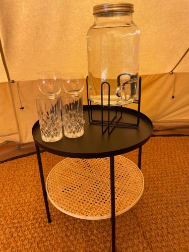 une table noire avec des verres et un bocal dessus dans l'établissement Glamping Tent Mariehamn, à Mariehamn